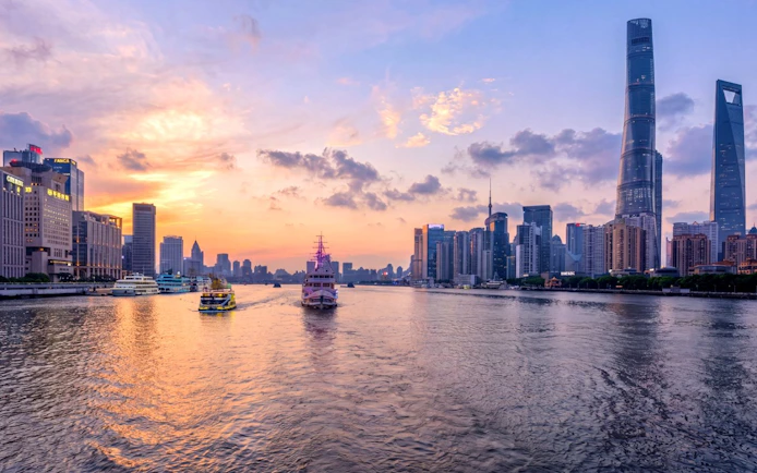 Shanghai skyline at sunset with historic Bund and modern Lujiazui across Huangpu River.