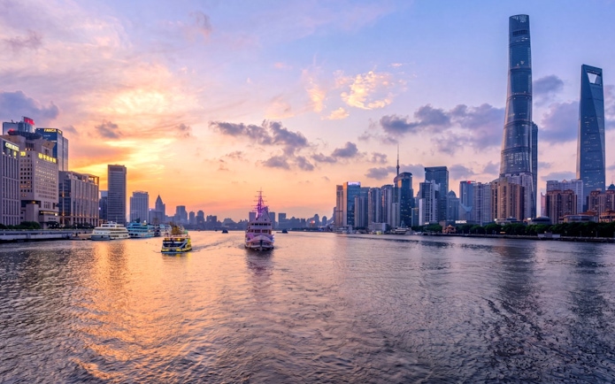 Shanghai skyline at sunset with historic Bund and modern Lujiazui across Huangpu River.