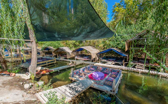 Outdoor seating area with traditional rugs over a stream in Cappadocia, Turkey.
