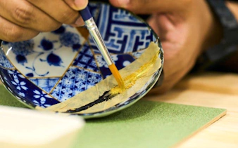 Kintsugi workshop in Shinjuku, Tokyo, repairing a ceramic bowl with gold lacquer.