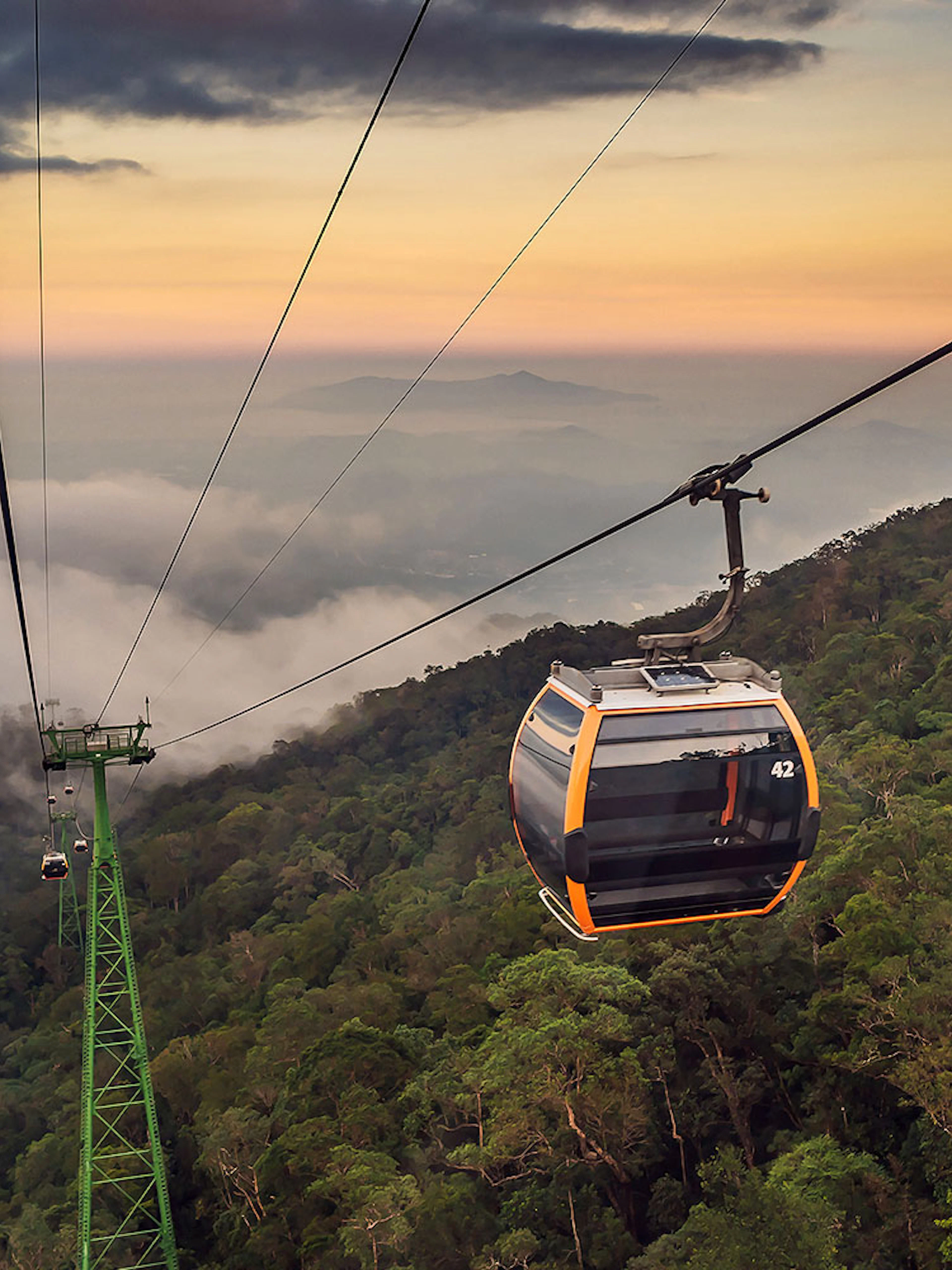 Cable car ascending over lush forest at Sun World Ba Na Hills, Vietnam.
