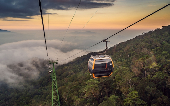 Cable car ascending over lush forest at Sun World Ba Na Hills, Vietnam.