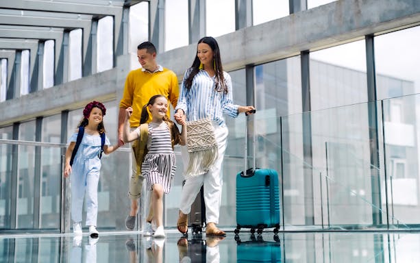 Family walking with luggage at Hong Kong Airport terminal.