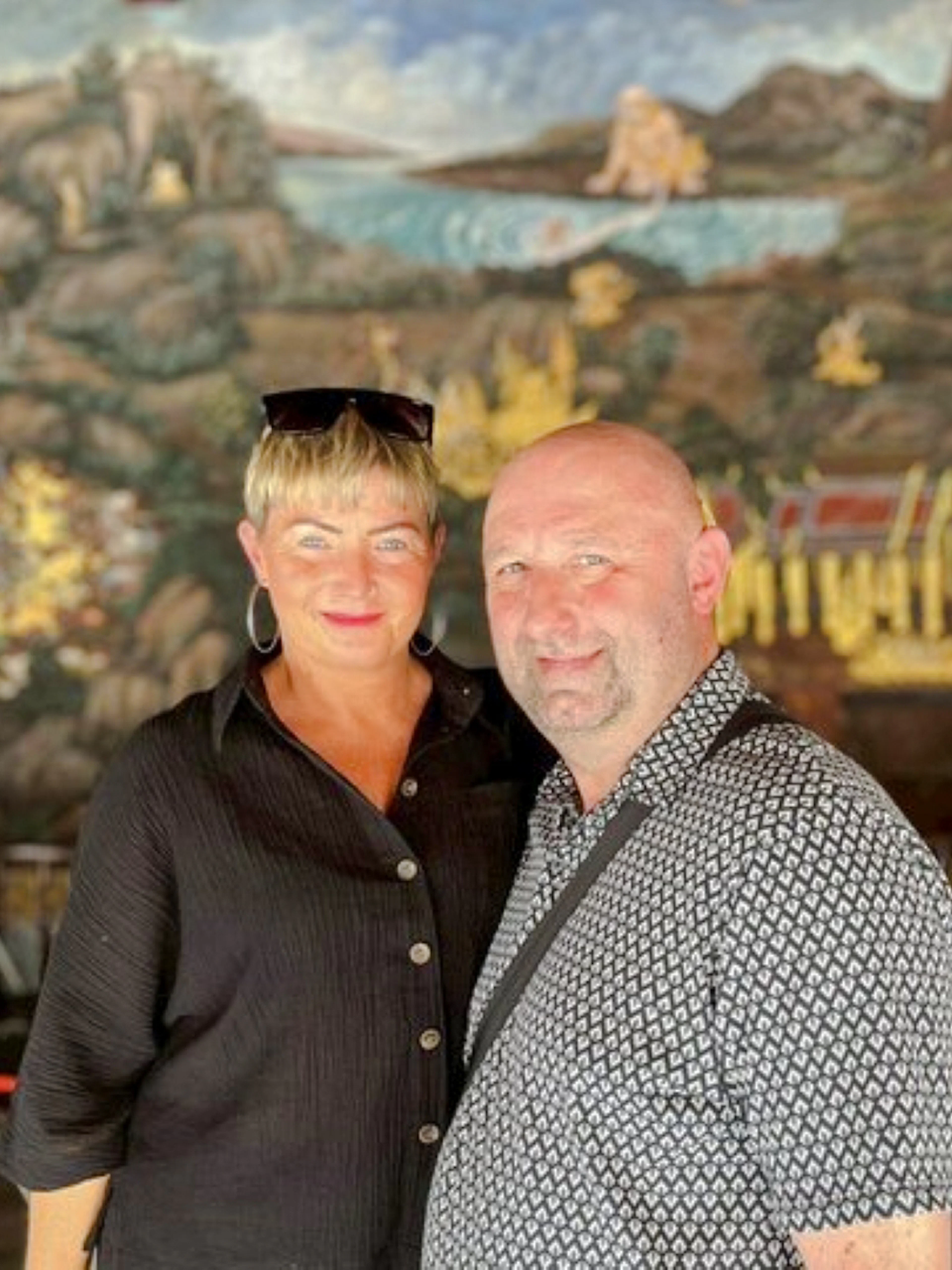 Visitors at Wat Pho with intricate mural backdrop, part of Grand Palace, Wat Pho & Wat Arun tour.