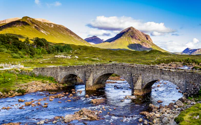 Stone bridge over river with Scottish Highlands in the background.