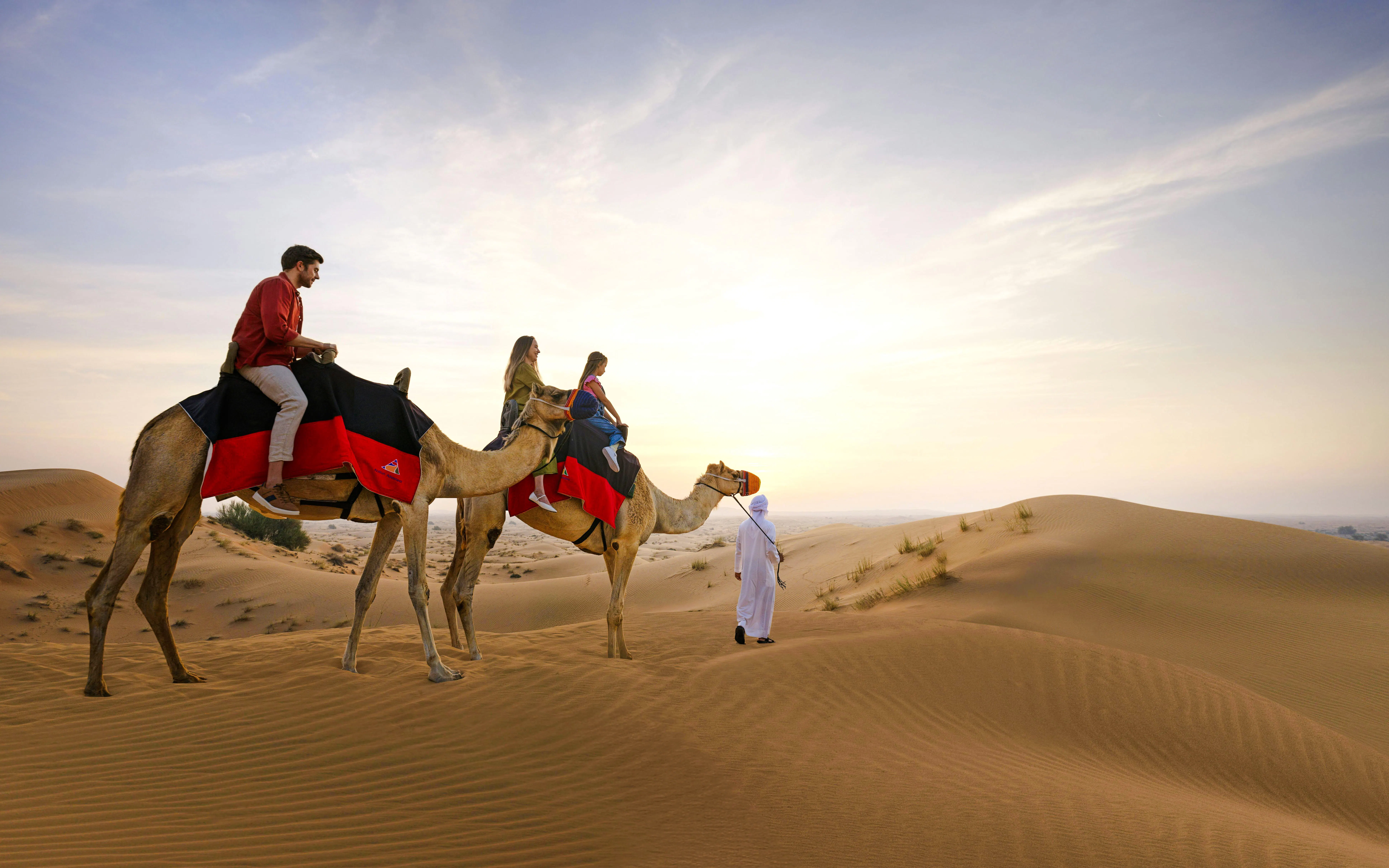 Camel ride through Dubai Desert dunes at sunset.