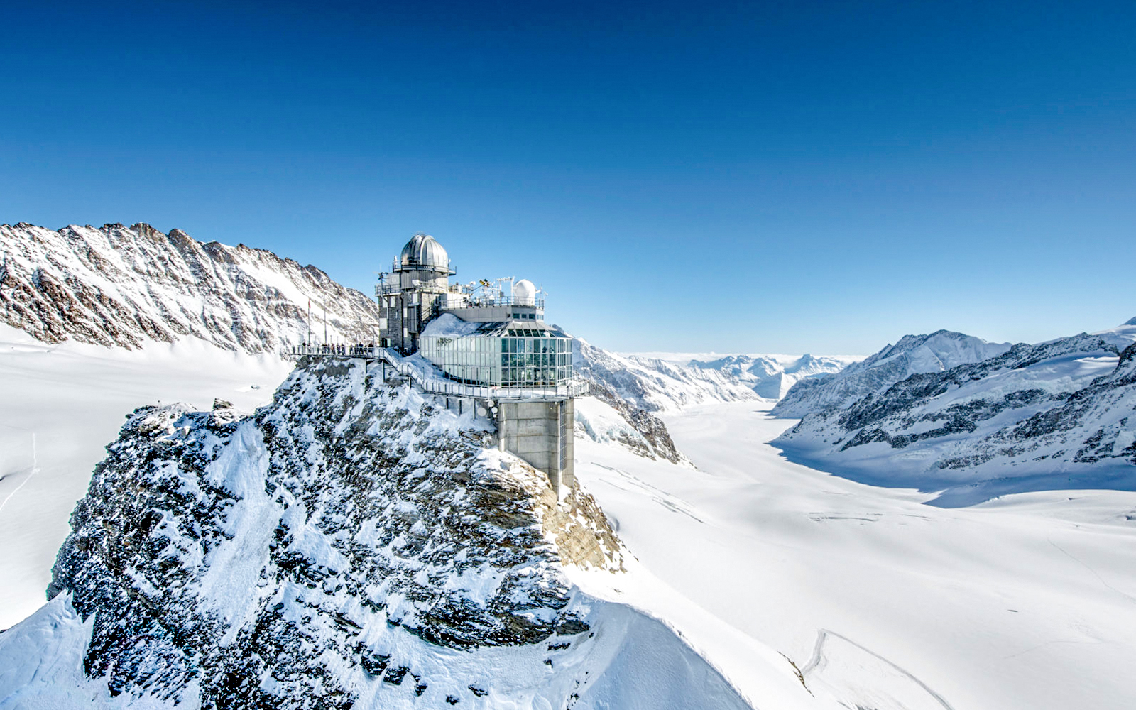 Jungfraujoch observatory on snowy peak with panoramic view of Swiss Alps.