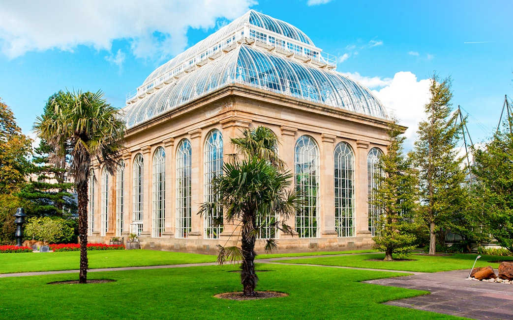 Greenhouse in Royal Botanic Gardens with palm trees and glass architecture.