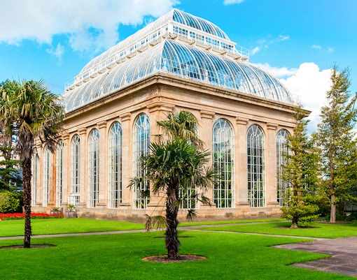 Greenhouse in Royal Botanic Gardens with palm trees and glass architecture.