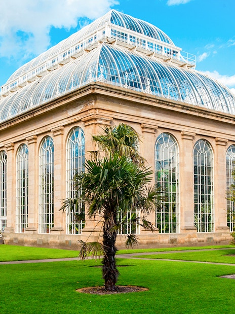 Greenhouse in Royal Botanic Gardens with palm trees and glass architecture.