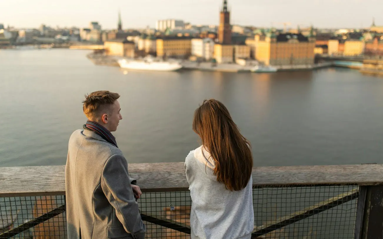 Couple overlooking Stockholm cityscape from a waterfront viewpoint.