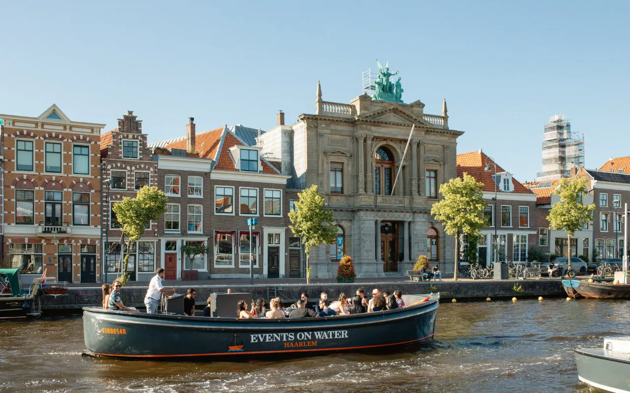 Boat tour on Haarlem canal passing historic buildings.