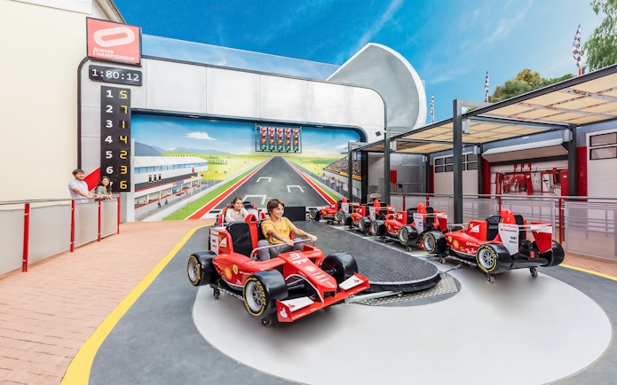 Junior championship ride at Ferrari Land with children in red race cars.