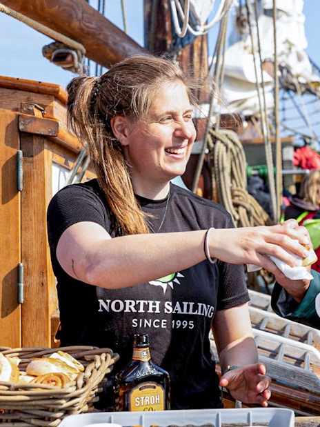 Crew serving hot chocolate and cinnamon buns to guests on a whale watching tour in Husavik.