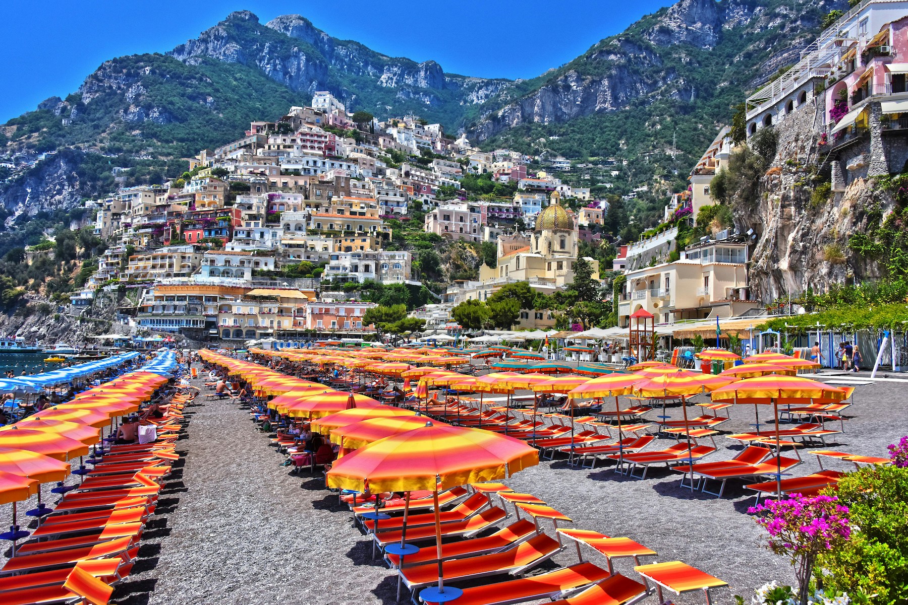 Postiano Spiaggia Grande beach with colorful umbrellas and sunbathers along the Amalfi Coast.