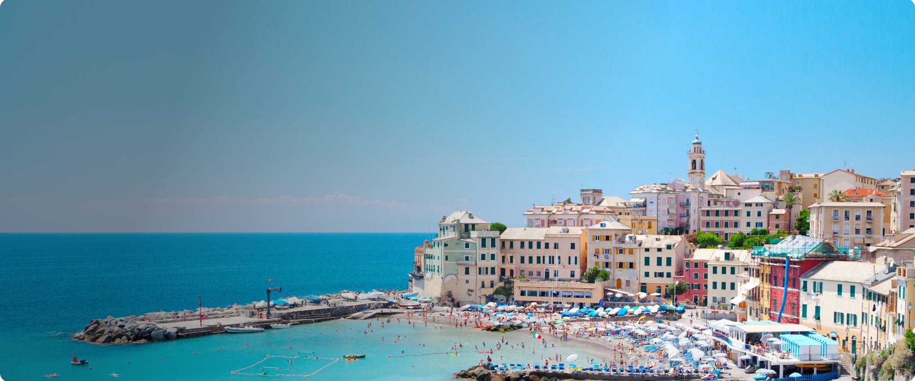Colorful buildings and beach in Genoa, Italy, with people enjoying the seaside.