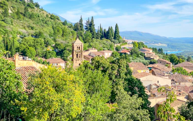 Village of Moustier Sainte Marie with bell tower and surrounding greenery in Provence, France.