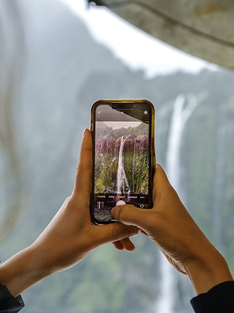 Visitor photographing waterfall at Milford Sound.