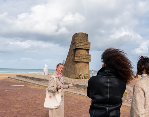 Guide explaining Omaha Beach Memorial to visitors in Normandy.