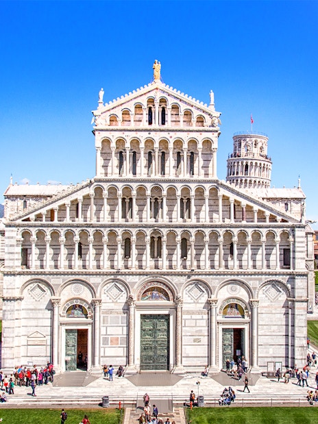 Primate Metropolitan Cathedral of Santa Maria Assunta in Pisa with tourists in the foreground.
