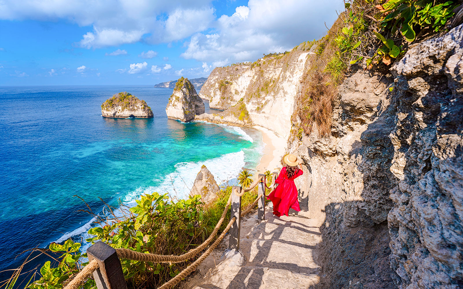 Staircase descent along rocky cliff to beach with ocean view in Bali.