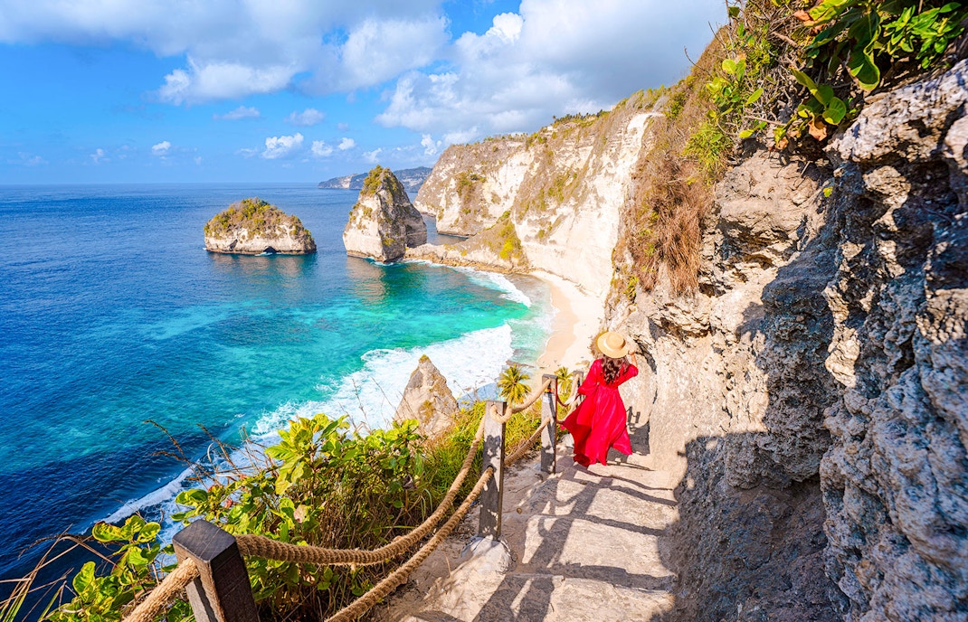 Staircase descent along rocky cliff to beach with ocean view in Bali.