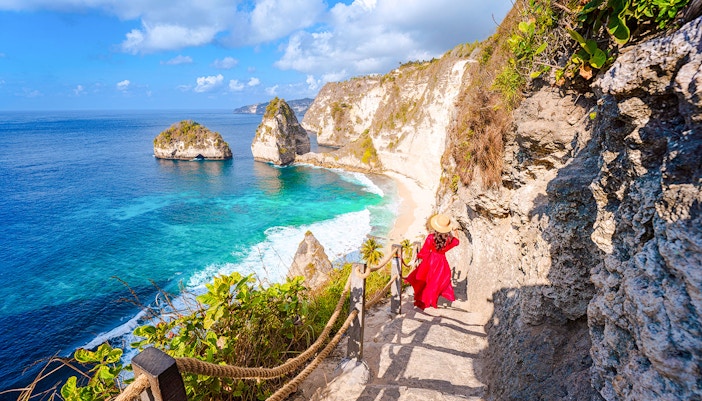 Staircase descent along rocky cliff to beach with ocean view in Bali.