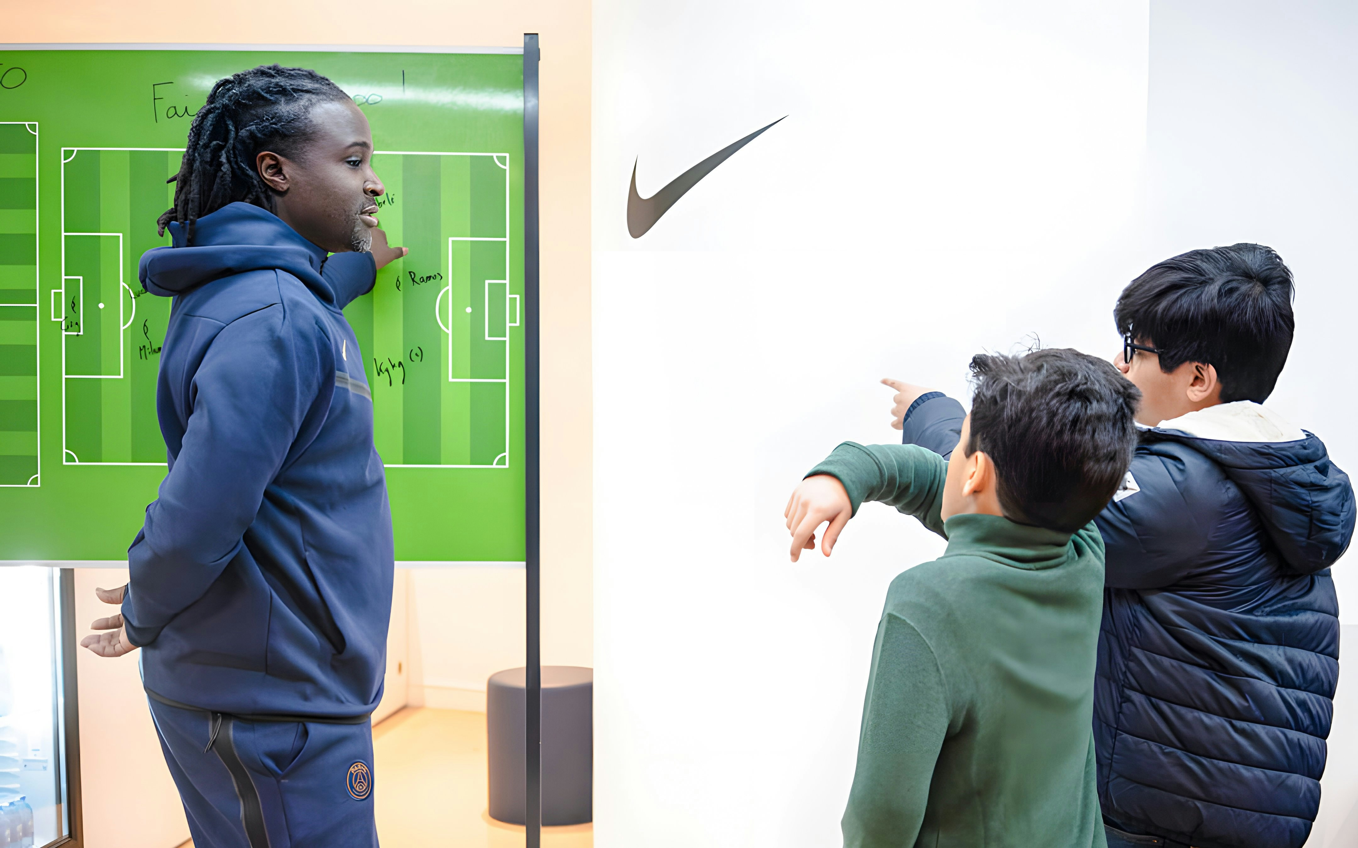 Coach explaining tactics to children at PSG Stadium, Paris, France.