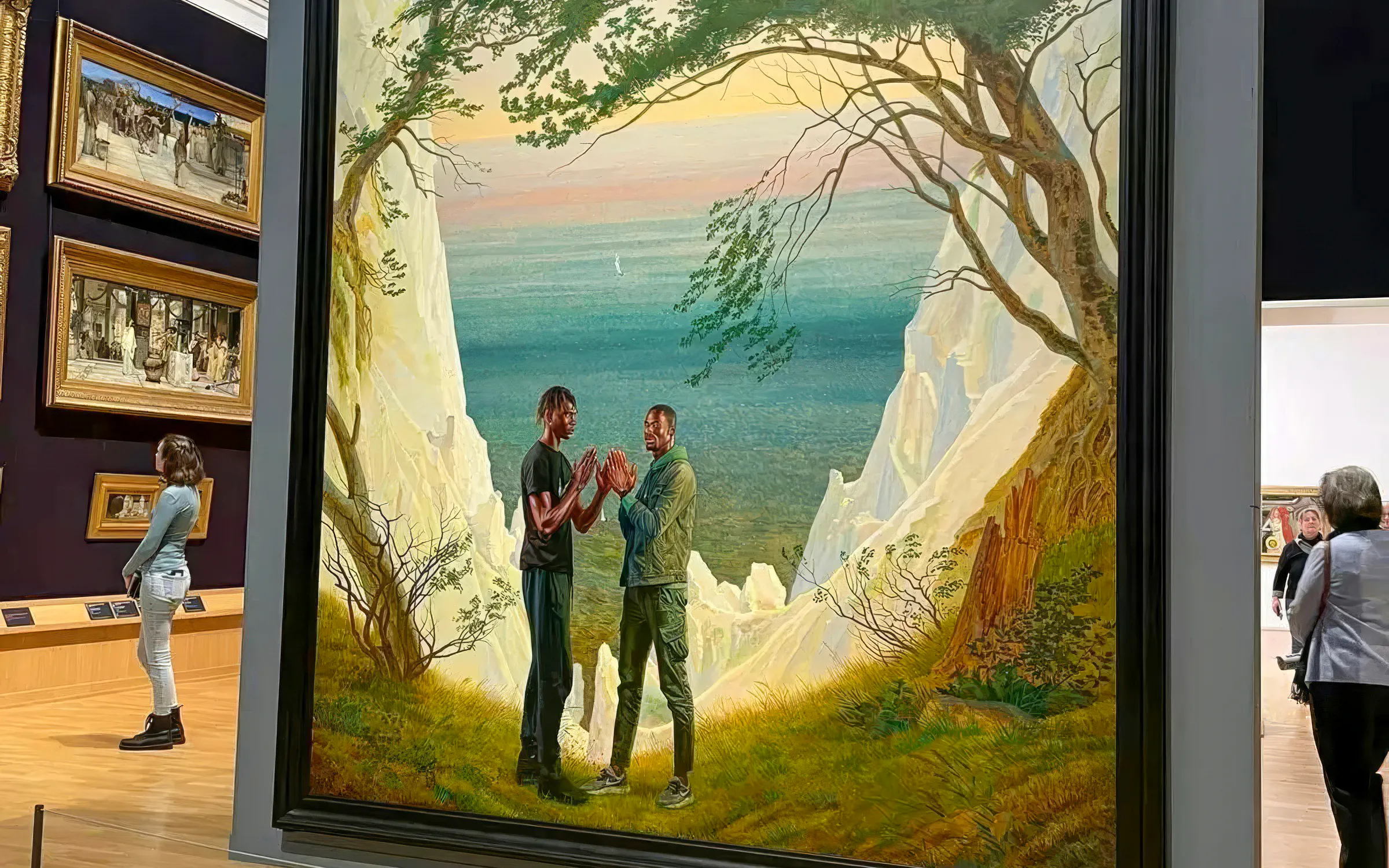 Painting of two men standing on a cliffside with a sea view, by Kehinde Wiley.