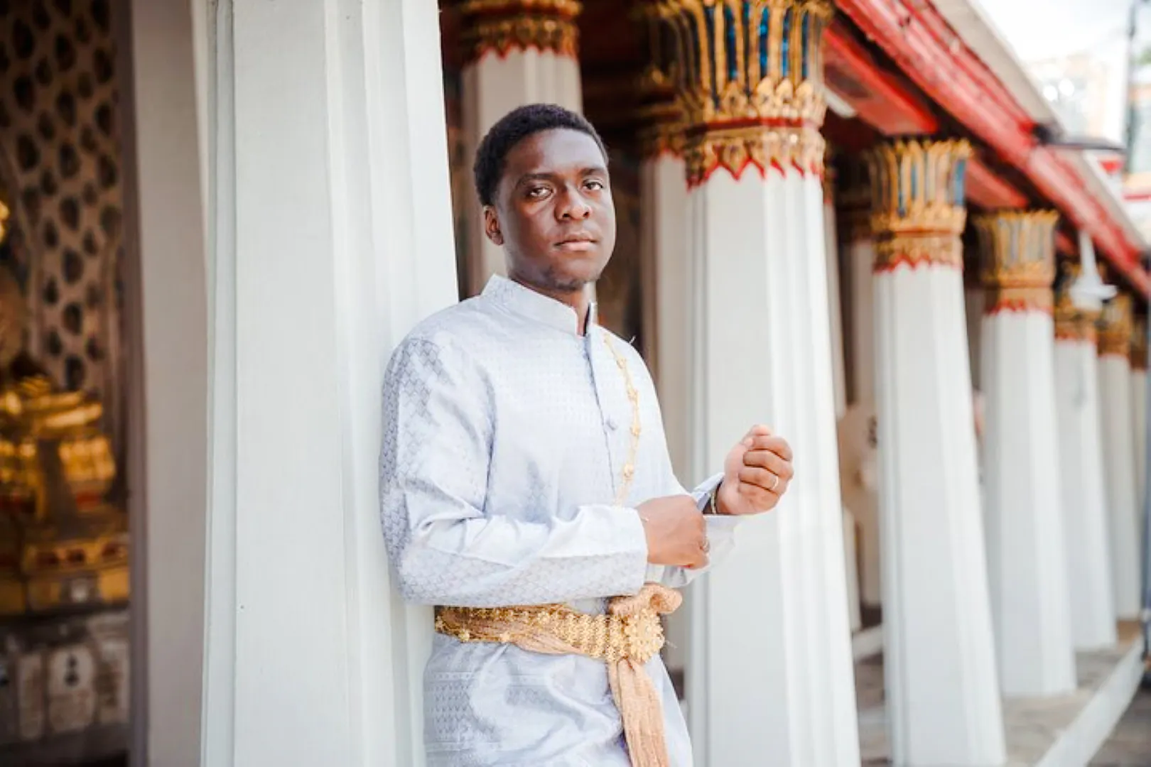 Person in traditional Thai attire at Wat Arun temple, Bangkok.