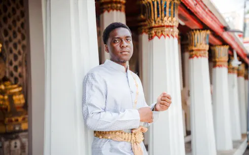 Person in traditional Thai attire at Wat Arun temple, Bangkok.