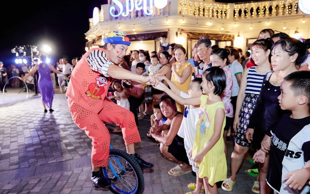 Performer on unicycle interacting with children at Sun World Hon Thom.