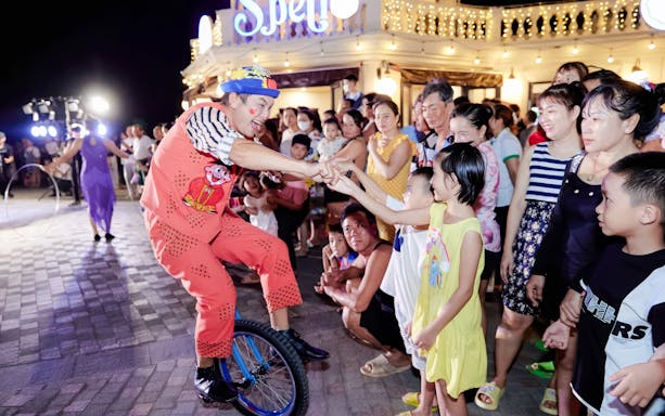 Performer on unicycle interacting with children at Sun World Hon Thom.