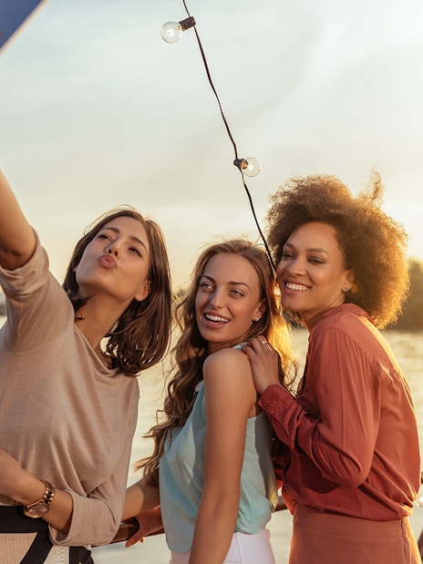 Tourists taking a selfie on a Douro River party cruise at sunset.