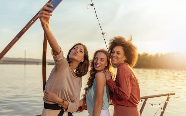 Tourists taking a selfie on a Douro River party cruise at sunset.