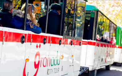 Granada city tour bus with passengers on a hop-on hop-off route.