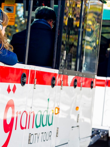 Granada city tour bus with passengers on a hop-on hop-off route.
