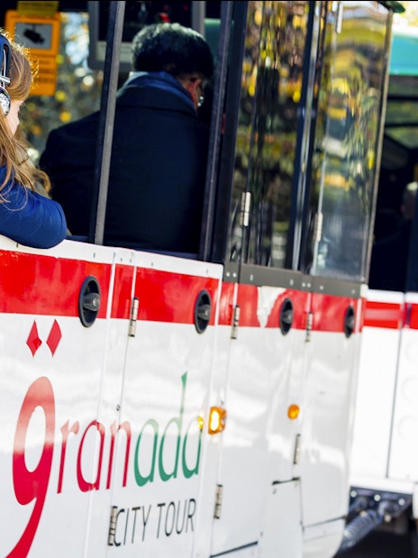 Granada city tour bus with passengers on a hop-on hop-off route.