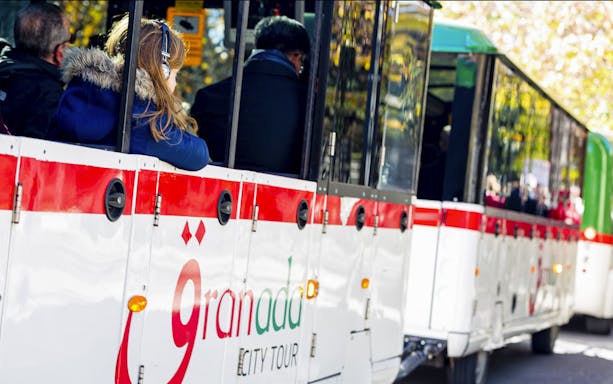 Granada city tour bus with passengers on a hop-on hop-off route.