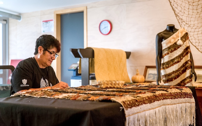 Craftsperson weaving traditional Māori garment at Te Puia, New Zealand.