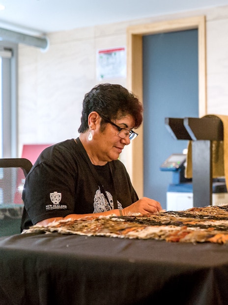 Craftsperson weaving traditional Māori garment at Te Puia, New Zealand.
