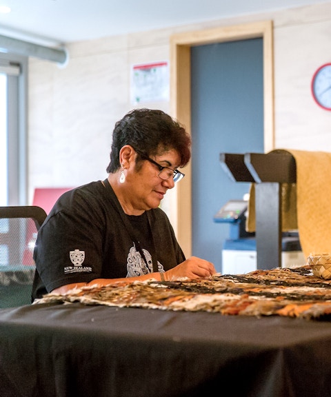Craftsperson weaving traditional Māori garment at Te Puia, New Zealand.