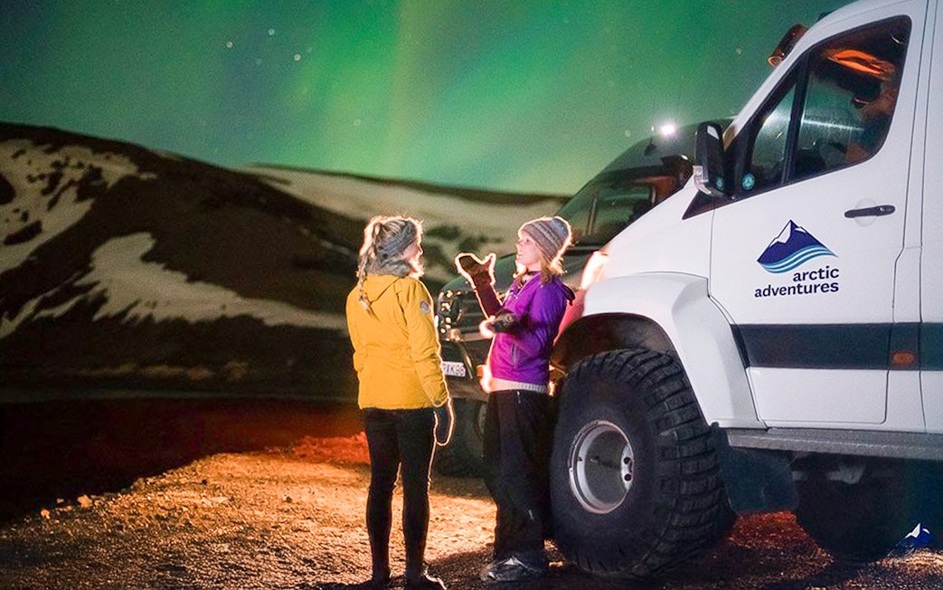 Guests viewing northern lights beside a Super Jeep on Premium Northern Lights Tour.