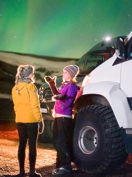 Guests viewing northern lights beside a Super Jeep on Premium Northern Lights Tour.