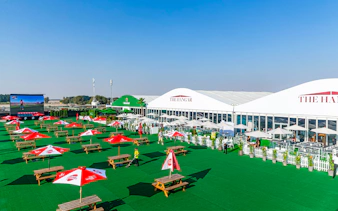 Outdoor seating area at Emirates Dubai 7s Sunroom Hospitality with tables and umbrellas.