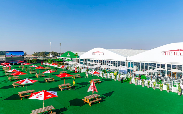 Outdoor seating area at Emirates Dubai 7s Sunroom Hospitality with tables and umbrellas.