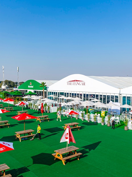 Outdoor seating area at Emirates Dubai 7s Sunroom Hospitality with tables and umbrellas.