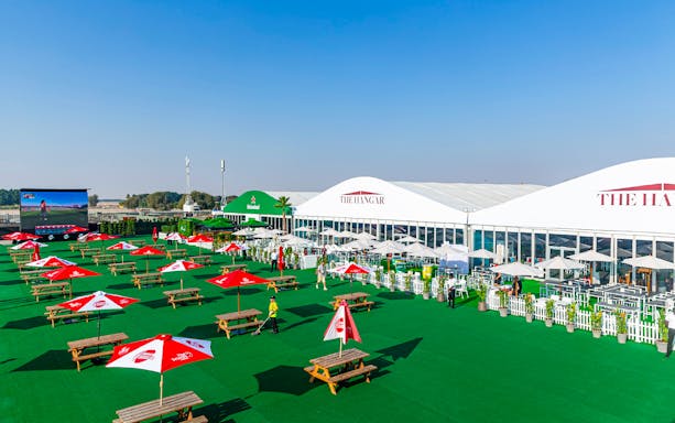 Outdoor seating area at Emirates Dubai 7s Sunroom Hospitality with tables and umbrellas.