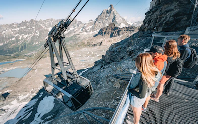 Cable car ascending Glacier with tourists viewing Matterhorn in Swiss Alps.