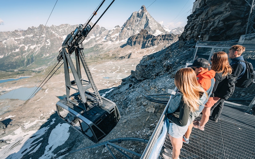 Cable car ascending Glacier with tourists viewing Matterhorn in Swiss Alps.